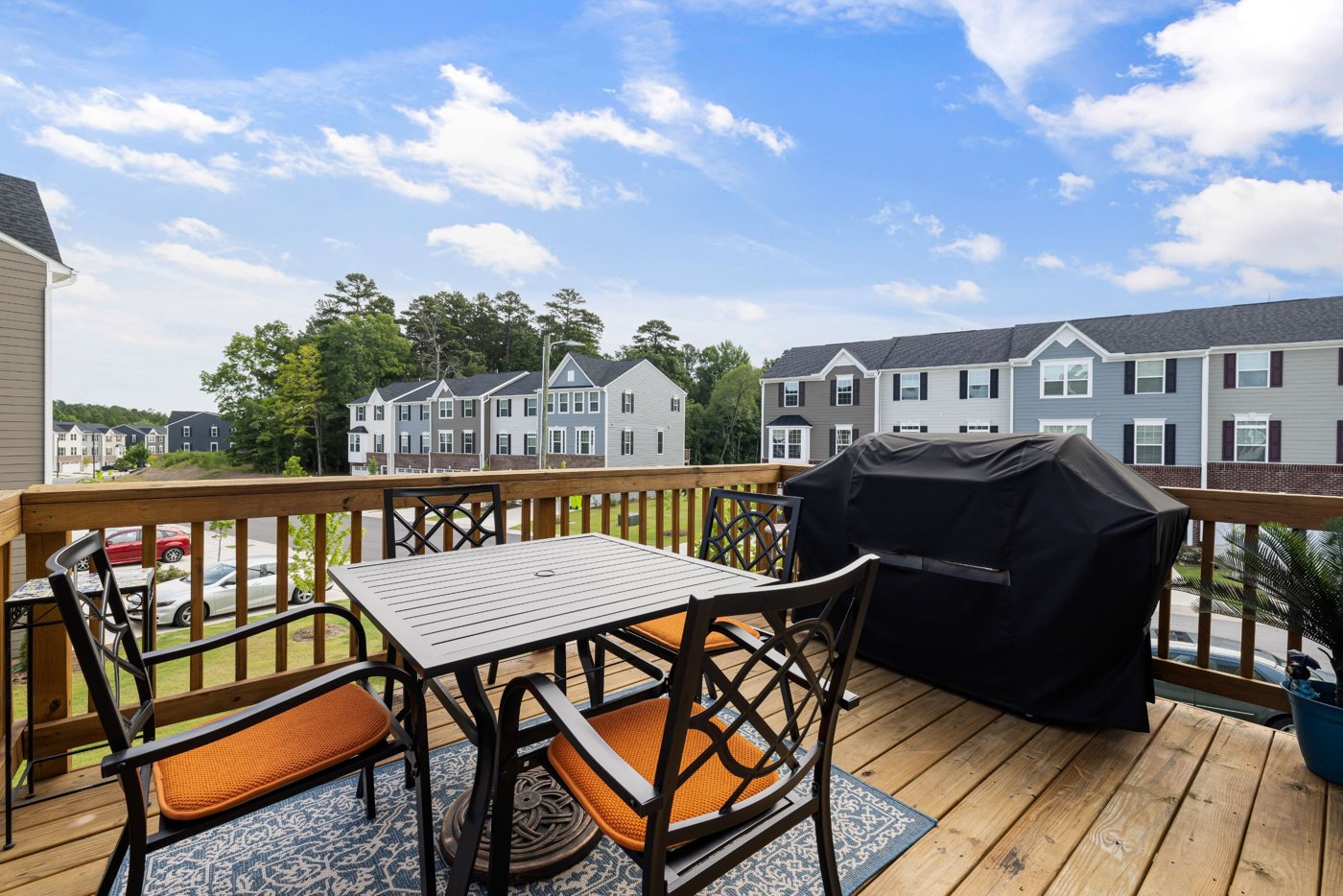 Wood deck with railing, patio dining set and grill on a sunny day