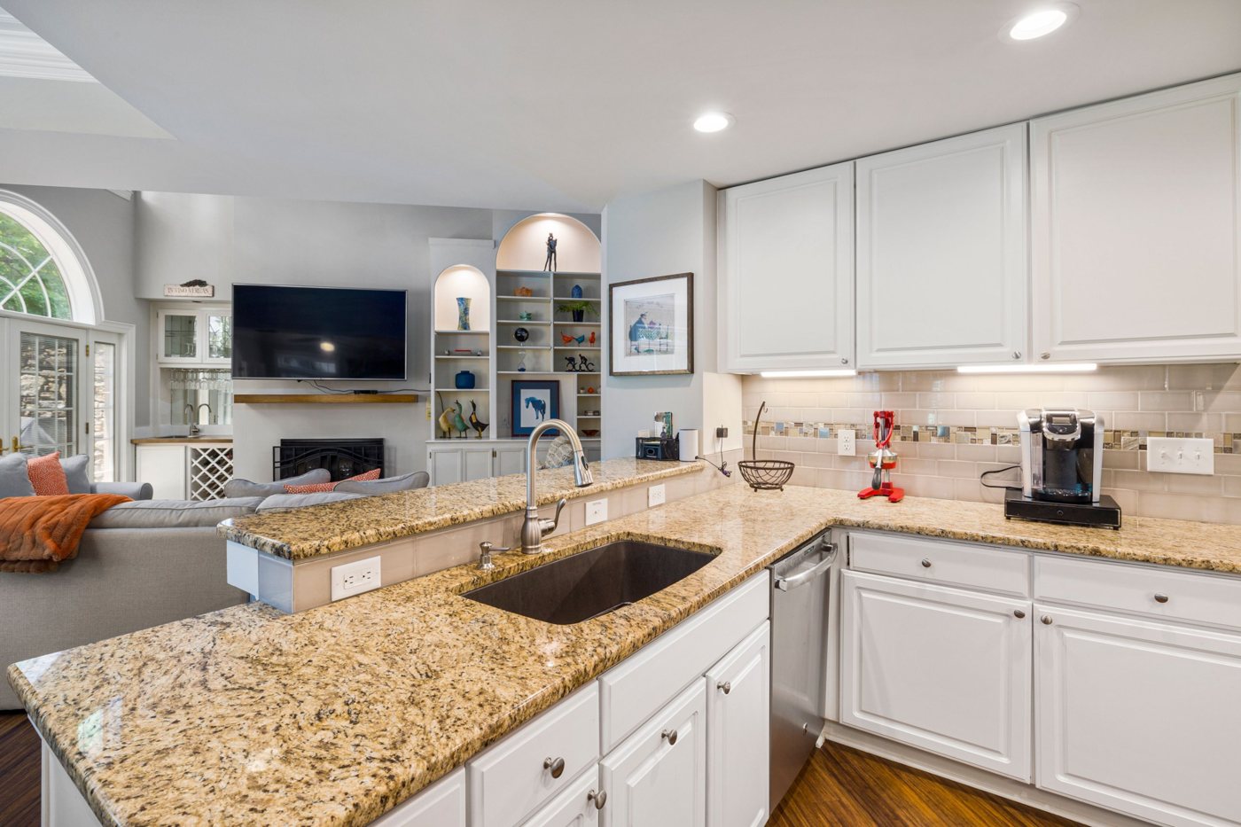 Kitchen with white cabinets, granite countertops and a tiled backsplash